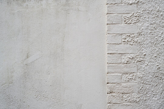 Off white rendered wall texture with weathered smooth surface and contrasting rough painted brickwork