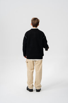 Back View of Young Asian Man Walking in Casual Streetwear Outfit with Coffee Cup on Minimalist Grey Studio Background