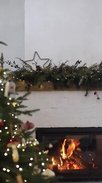 Vertical Video of Cozy Christmas Fireplace Decorated with Garland and Lights, video. Holiday Home Decor. Festive Atmosphere, Hygge Christmas Eve