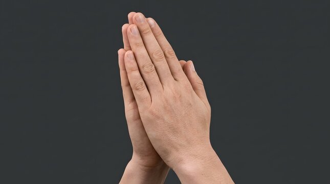 Hands folded in prayer or namaste gesture isolated on dark gray background representing faith hope and spirituality