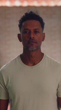 African American man standing indoors with neutral expression in thoughtful contemplation