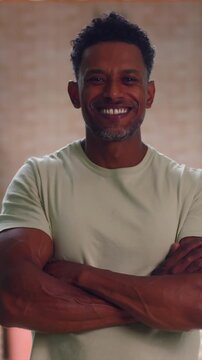 African American man standing with arms crossed smiling confidently in modern interior