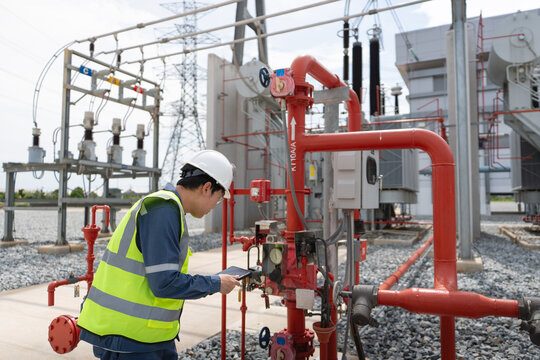 Fire protection system inspection is performed by a technician using a tablet beside the valve and gauge in a transformer bay