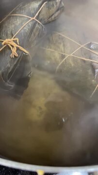 Hallacas boiling in pot close up bubbling water steam