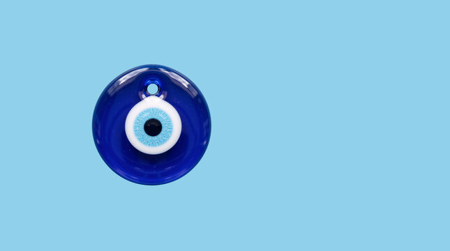 Blue evil eye charm floating on light blue background