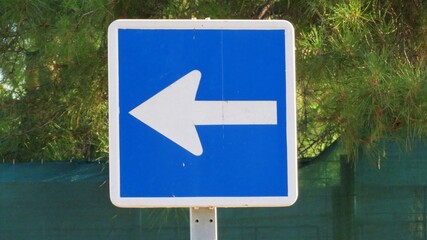 An informational road sign featuring a white arrow on a blue background in Madrid, Spain, indicating a direction of travel or a one-way street to the left.September 16, 2026 © GenadiyGM