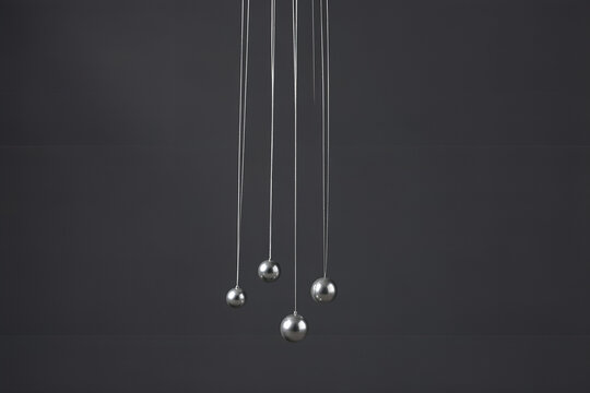 centered still life of silver threads with beads against charcoal