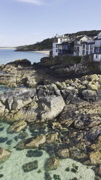 Spectacular vertical landscape of a golden hour sunset glowing over the beautiful Cornish coastline, ocean waves, and the bay of St Ives.