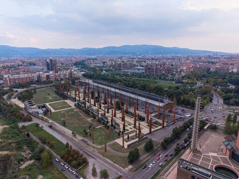 Aerial view of Parco Dora with its distinctive steel pillars, industrial structures, and landscaped park areas set against the urban skyline of Turin, Piedmont, Italy.