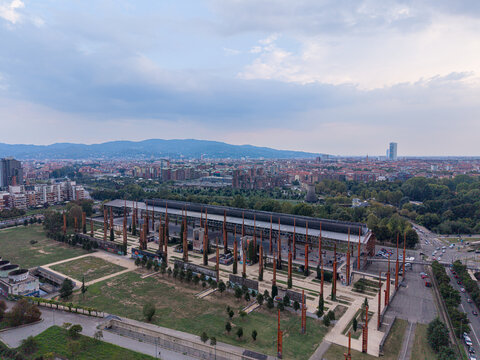 Aerial view of Parco Dora with its iconic steel pillars and industrial structures set against the urban skyline and distant mountains in Turin, Piedmont, Italy.