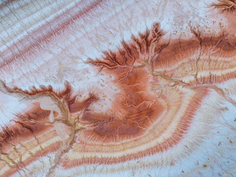 Aerial view of the intricate red and white geological erosion patterns and dry riverbeds in the desert landscape of Mangistau, Mangystau Region, Kazakhstan.