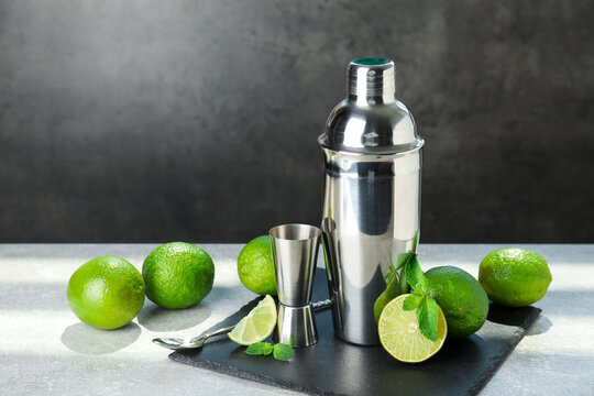 Ingredients for mojito, shaker, jigger and spoon on light grey table. Space for text
