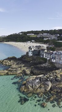 Vertical view of the picturesque St Ives harbor in Cornwall, featuring traditional fishing boats, calm waters, and coastal town architecture.