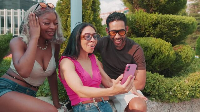 Excited diverse friends making a video call outdoors