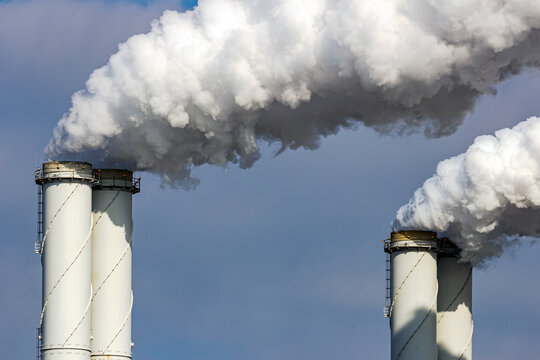 Close-up of industrial chimneys releasing smoke and emissions from a power plant, illustrating industrial air pollution