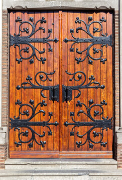 Old wooden Gothic double door on a historic building, featuring ornate decorative ironwork and traditional craftsmanship.