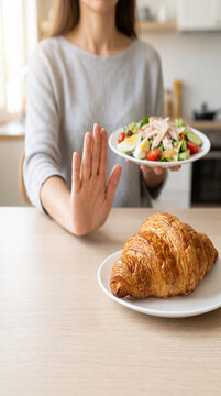 Woman refusing a croissant while choosing a plate of fresh salad and healthy food, representing mindful eating, diet change, weight management and healthier food choices