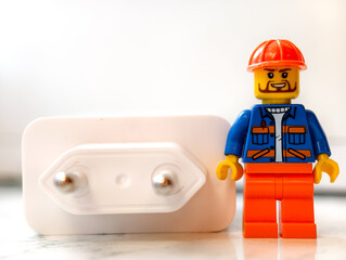 Fototapeta premium Russia, St. Petersburg, August 8, 2020 A small Lego man standing next to an electrical outlet