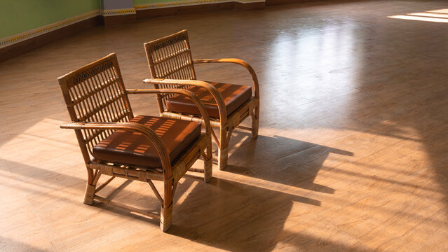 Two rattan chairs with brown leather seats placed on wooden floor in vintage sunlit room with warm sunlight