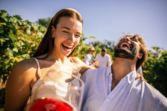 Happy couple enjoying wine together in a sunny vineyard