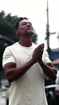 African American man smiling with clasped hands looking upward in faith, gratitude, and hope