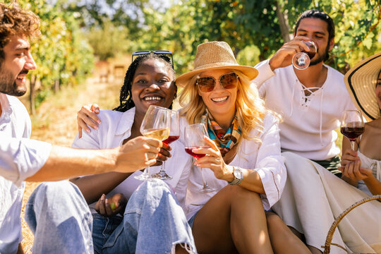 Happy friends raising wine glasses together in a vineyard