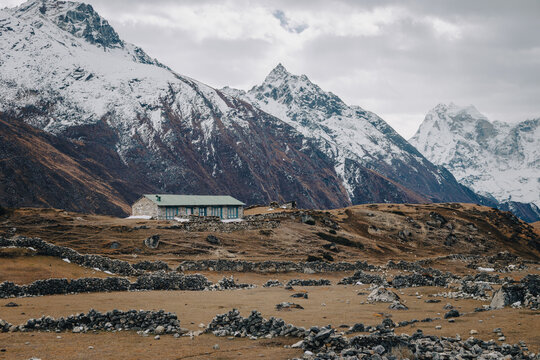 Remote Himalayan Mountain Lodge Beneath Snow Covered Peaks and Rugged Alpine Landscape