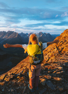 Child girl hiker tourist climbing mountains in Norway family travel vacations outdoors hiking tour active lifestyle, adventure eco tourism happy kid with backpack gear raised hands childhood moments