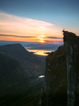 Kjerna mountain landscape in northern Norway with hiker on steep rock edge at sunset aerial scenery outdoor, trekking solo extreme adventure active healthy lifestyle freedom exploration concept