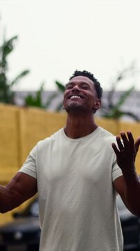 African American man standing with arms raised and head tilted back in joyful spiritual gratitude