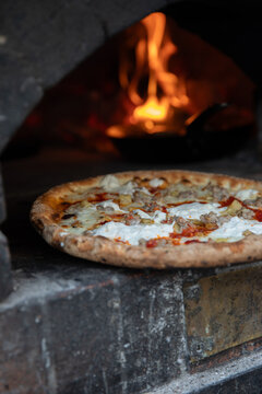 Freshly made pizza being put into wood fired oven