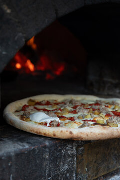 Freshly made pizza being put into wood fired oven