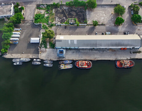 Aerial view of Rio Higuamo showing moored tugboats and industrial warehouses along the riverbank in San Pedro de Macoris, Dominican Republic.