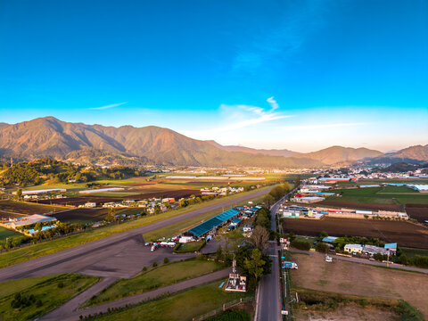 Aerial view of agricultural plantations and rolling mountains at sunrise in the valley of Constanza, La Vega Province, Dominican Republic.