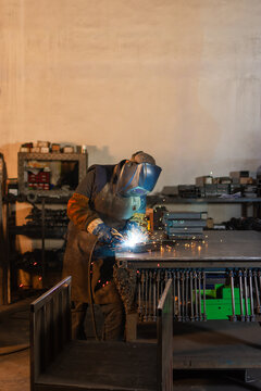 Full body industrial welder working with metal at workshop