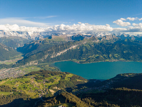 Aerial view of the Niederhorn mountain range overlooking Lake Thun, with the village of Sigriswil, green alpine meadows, and snow-capped peaks in Sigriswil, Canton of Bern, Switzerland.
