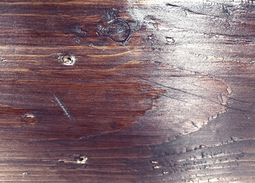 Weathered mahogany wood surface with dark grain markings and circular knots suitable for vintage furniture restoration projects and professional background usage.