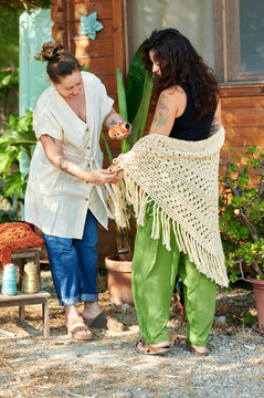 Female artisans discussing handmade crocheted shawls outdoor
