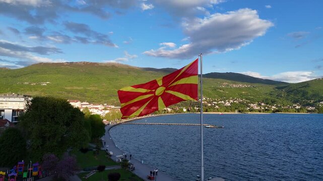 Aerial drone view of Ohrid city in North Macedonia with the North Macedonia flag waving in the wind. Lake Ohrid in the background.	