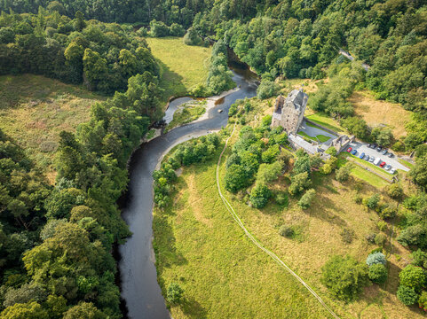 Aerial view of Neidpath Castle situated on the banks of the River Tweed, surrounded by lush green forests and meadows in Peebles, Scotland, United Kingdom.