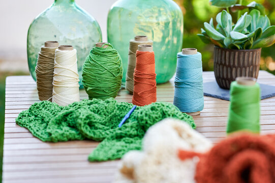 Colorful yarn spools and crochet work on wooden table