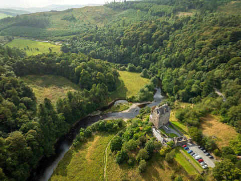 Aerial view of Neidpath Castle situated along the River Tweed, surrounded by lush green forests and rolling hills in Peebles, Scotland, United Kingdom.