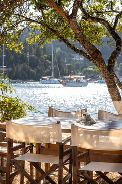 Restaurant table overlooking the Mongonissi Beach and bay on Paxos island, Greece. Focus on foreground, backlit by low standing sun. Tranquility