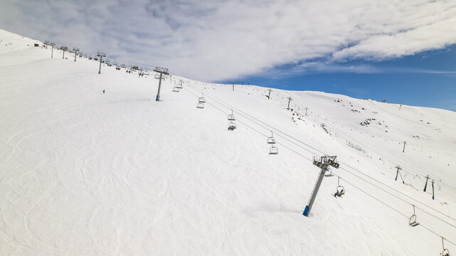 Aerial view of Cerro Catedral ski resort with chairlifts carrying skiers over snow-covered slopes under a bright blue sky in Bariloche Department, Rio Negro Province, Argentina.