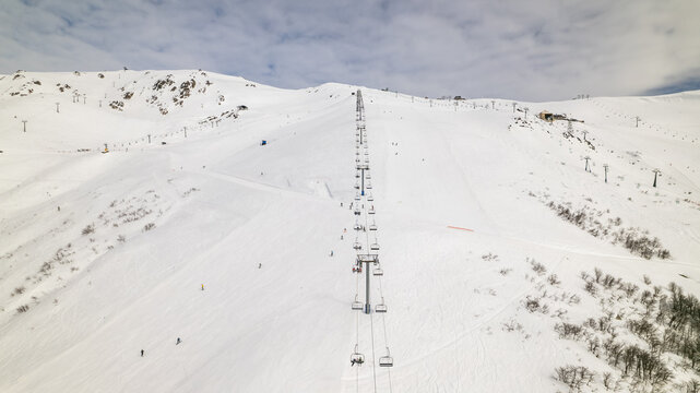 Aerial view of the Cerro Catedral ski resort featuring a chairlift ascending snow-covered slopes with skiers and snowboarders in Bariloche Department, Rio Negro Province, Argentina.