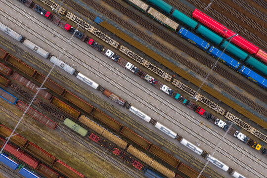 Aerial view of industrial railway yard with multiple freight trains and colorful cargo containers on parallel tracks in Breclav, South Moravian Region, Czechia.