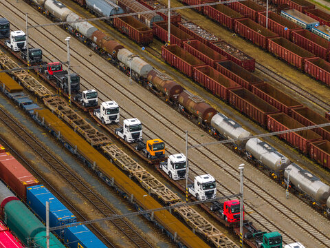 Aerial view of a freight train transporting semi-trucks through an industrial railway yard in Breclav, South Moravian Region, Czechia.
