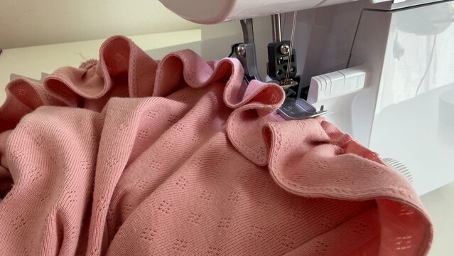 Aesthetic sewing workspace with an overlock machine, serger, fabric, threads and sewing accessories. Cozy atmosphere, the art of sewing, handmade fashion and garment making in a bright sewing studio