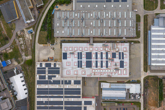 Aerial view of an industrial facility with large warehouse buildings, solar panel arrays on rooftops, and skylights in Breclav, South Moravian Region, Czechia.