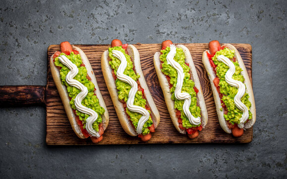 Chilean Completo Italiano. Hot dog sandwiches with tomato, avocado and mayonnaise on wooden board. Top view.
